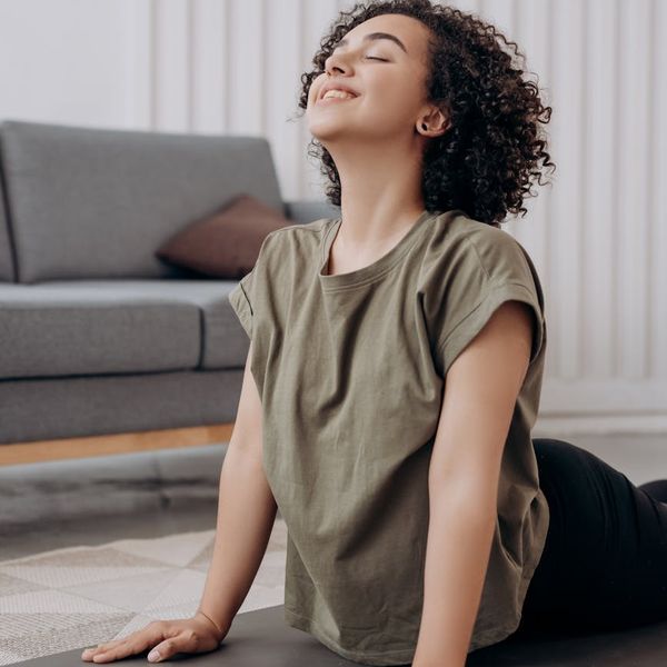 Smiling woman stretching gently on a yoga mat at home.